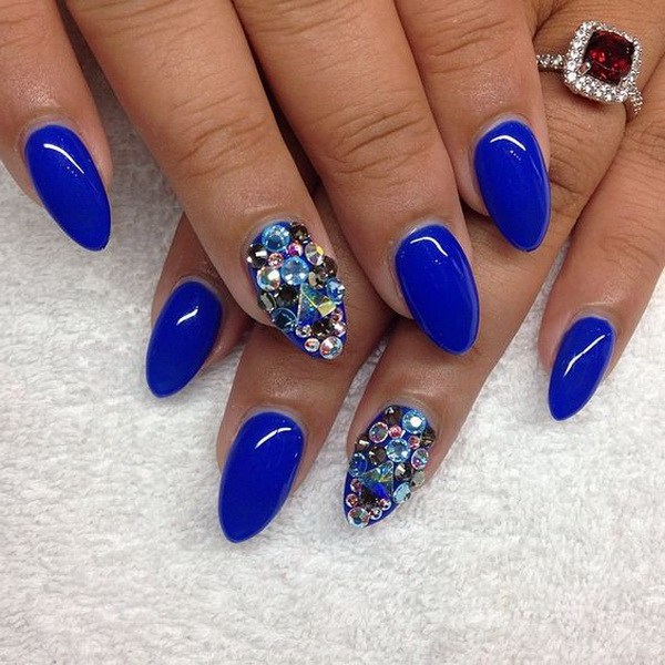 Uñas con forma de almendra azul con detalles de gemas. 