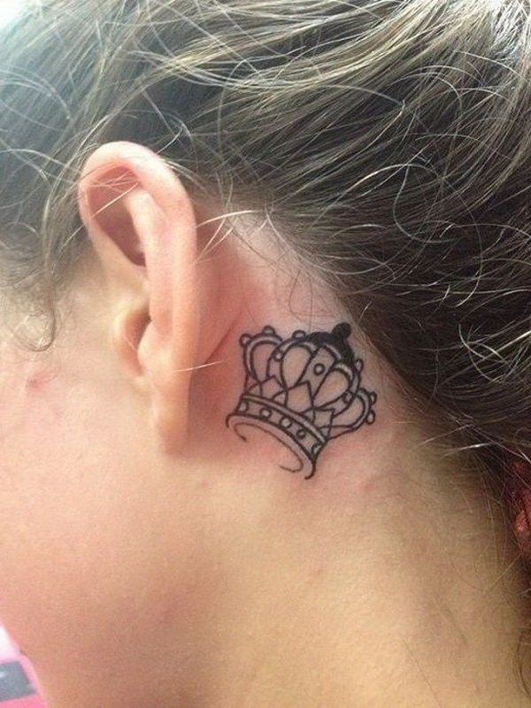 Tatuaje de la corona detrás de la oreja. 
