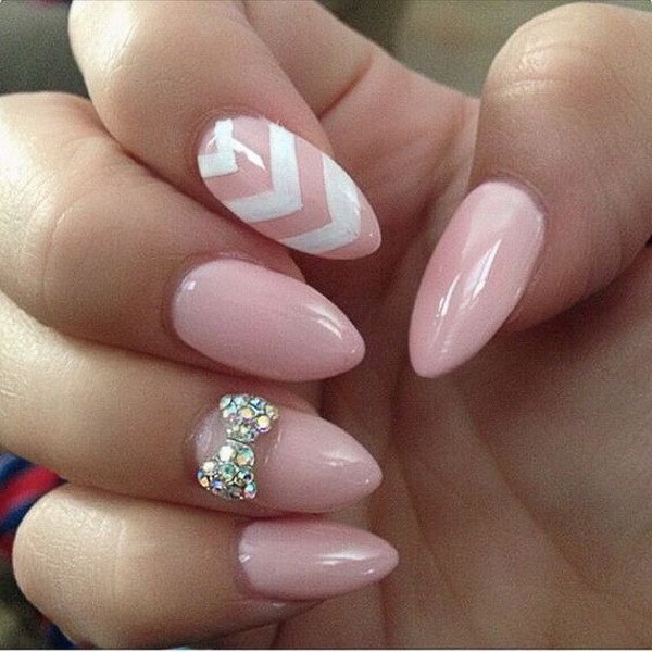Baby Pink Almond Nails con un arco tachonado y líneas blancas de Chevron. 