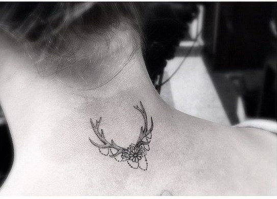 Tatuaje de ramas y flores en la parte posterior del cuello. 