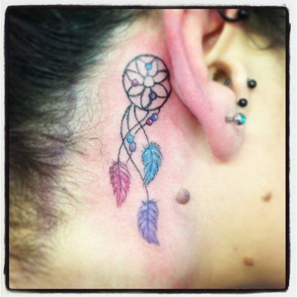 Colorido tatuaje Dreamcatcher detrás de la oreja. 