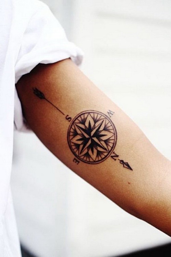 Tatuaje de brújula con flecha en el brazo. 