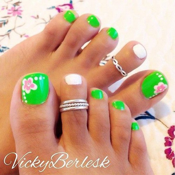 Uñas verdes frescas del dedo del pie con las flores blancas y rosadas. 