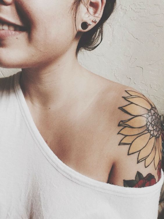 Cálido tatuaje de girasol en el hombro. 