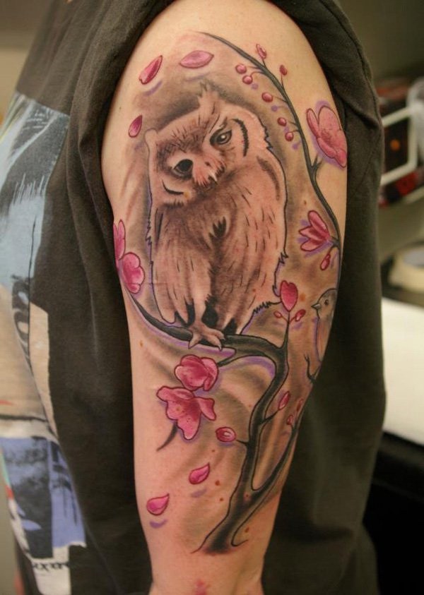 Búho con tatuaje de flores de cerezo.  Más a través de https://forcreativejuice.com/attractive-owl-tattoo-ideas/ 