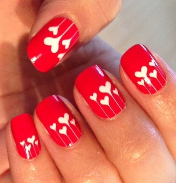 Diseño de uñas rojas con corazones blancos. 