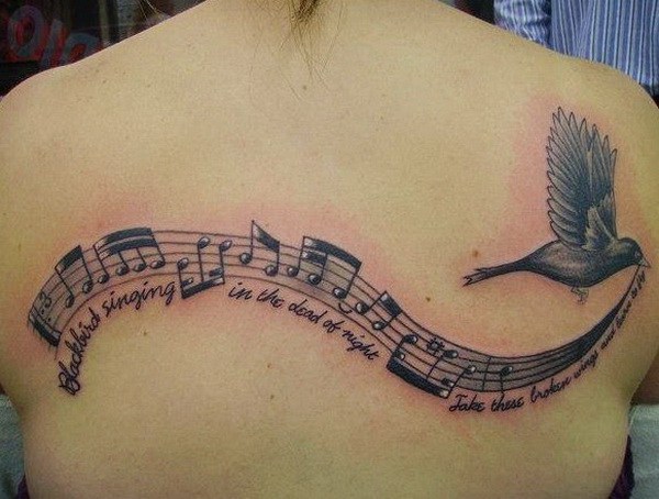 Notas musicales y letras con un pájaro es Flying Tattoo On Back. 