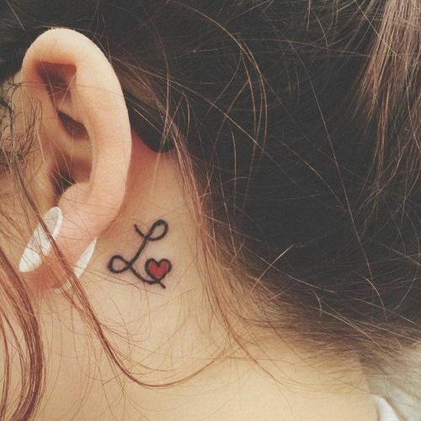 Letra L con un corazón rojo detrás del tatuaje del oído. 