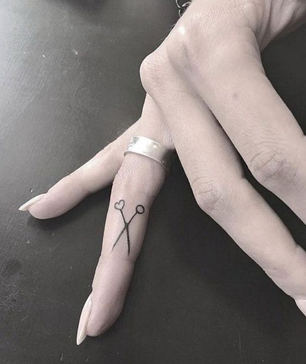 Tatuaje de tijera minimalista en el dedo. 